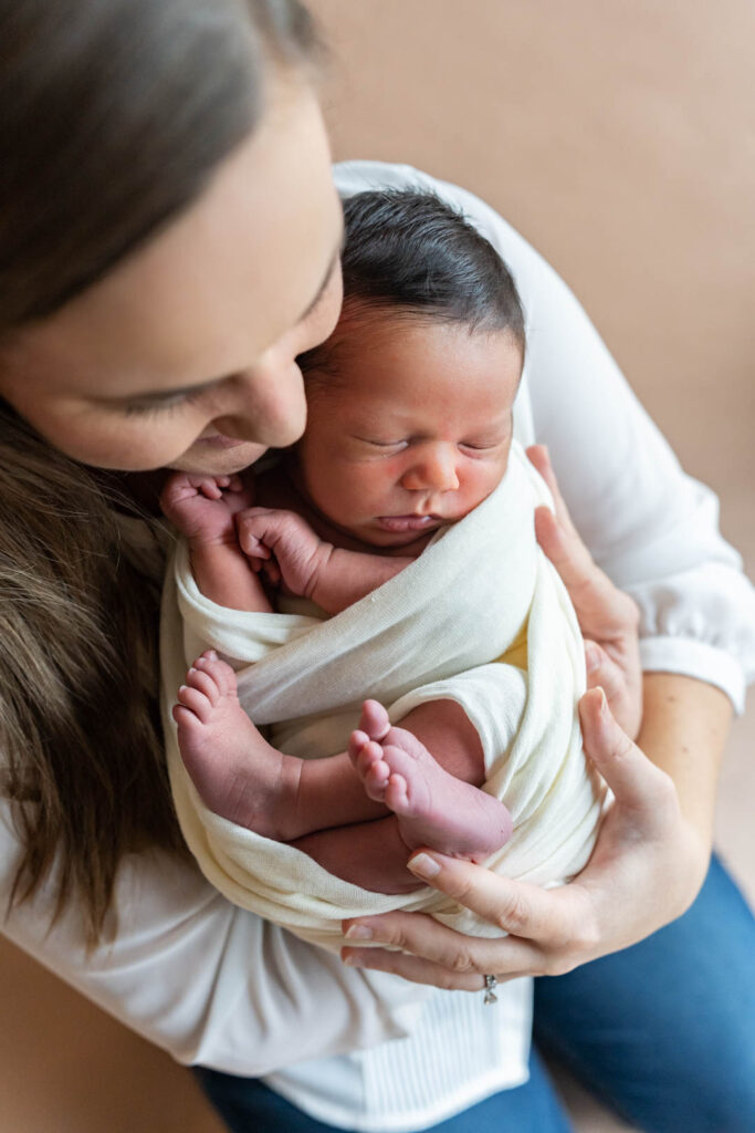 image of a mother holding her newborn wrapped in a cream colored wrap