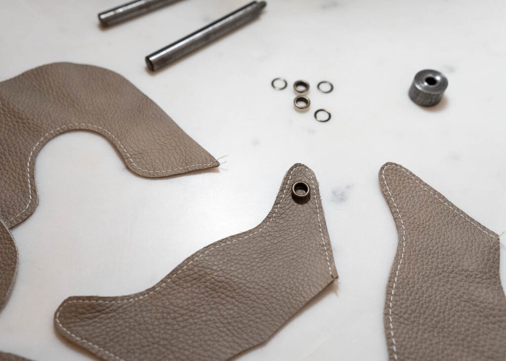 tools, grommets, and pieces of leather for making leather baby shoes