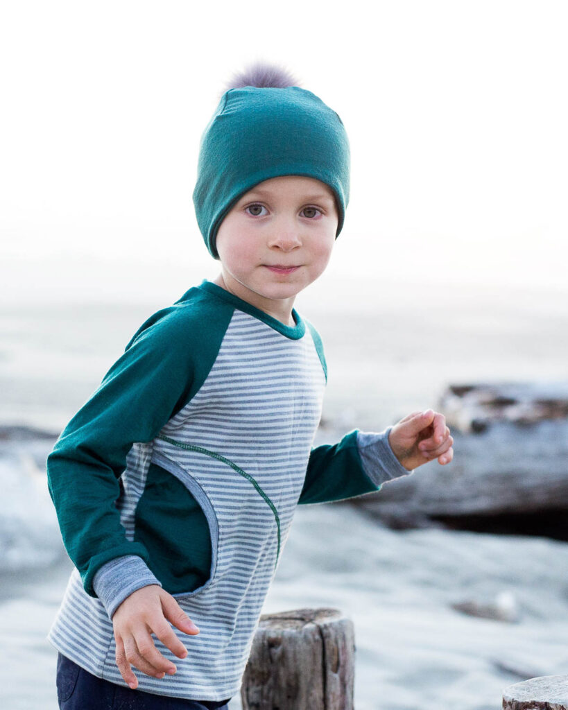a boy wearing a merino wool longsleeve shirt and a merino wool hat