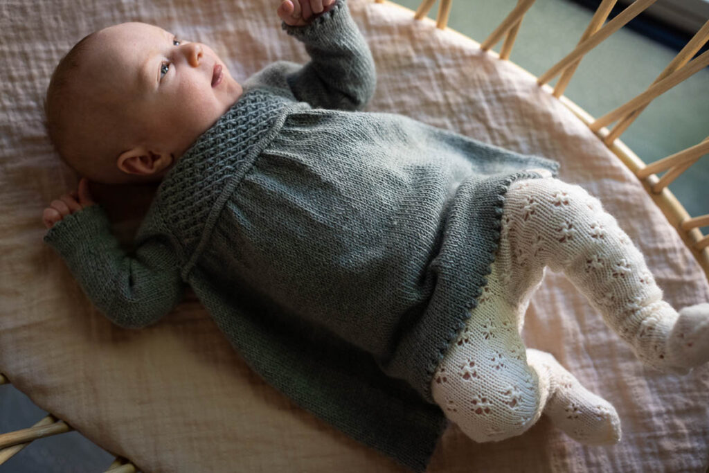 A baby girl wearing a knitted dress and tights