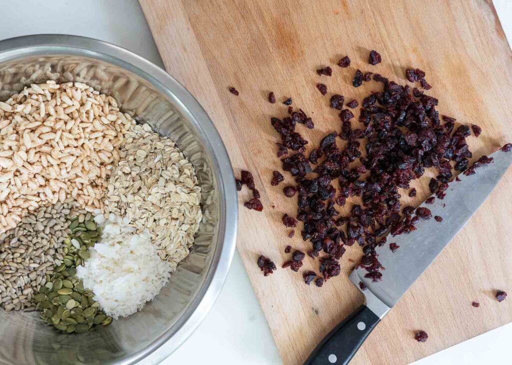 a cutting board with chopped cranberries for homemade granola bars